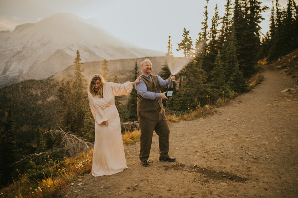 bride and groom popping champagne on a trail in Washington