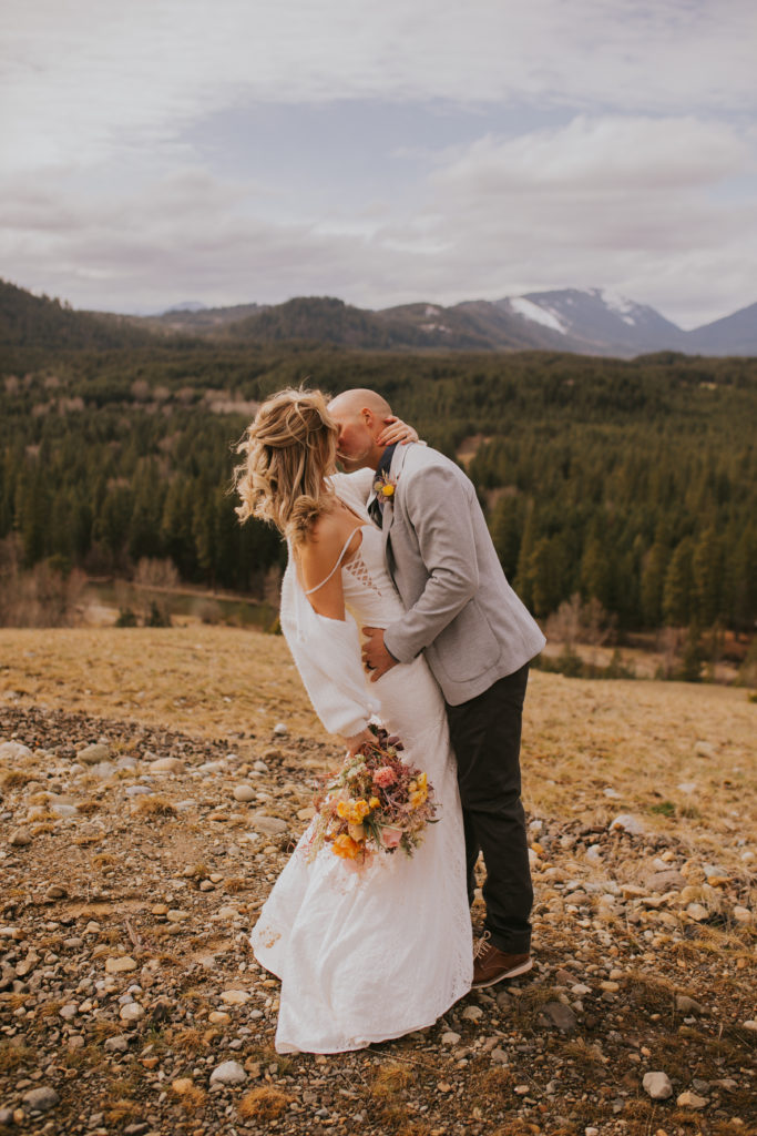 just married couple kissing on top of a mountain