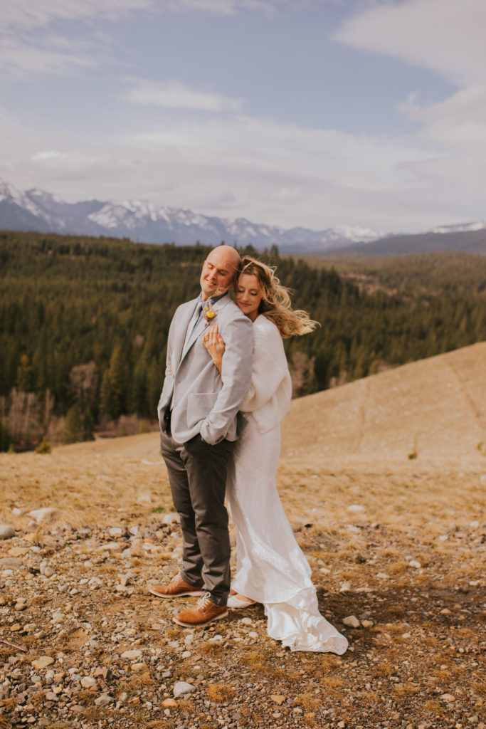 Suncadia couple hugging from behind in a windy day on a mountain