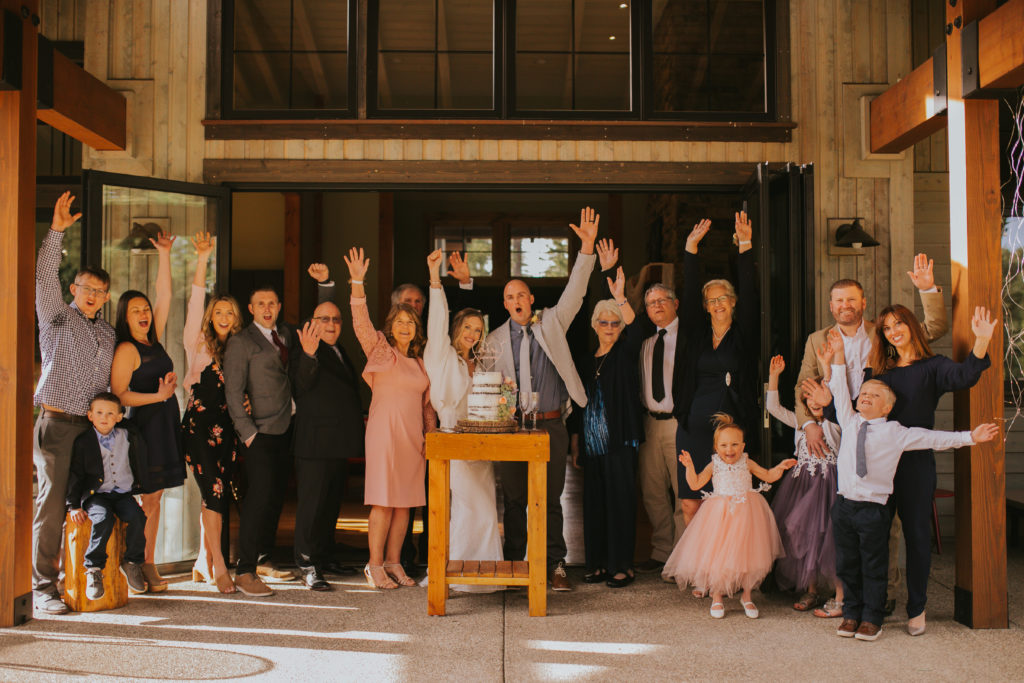 bride and groom immediate family members excited with hands in the air together