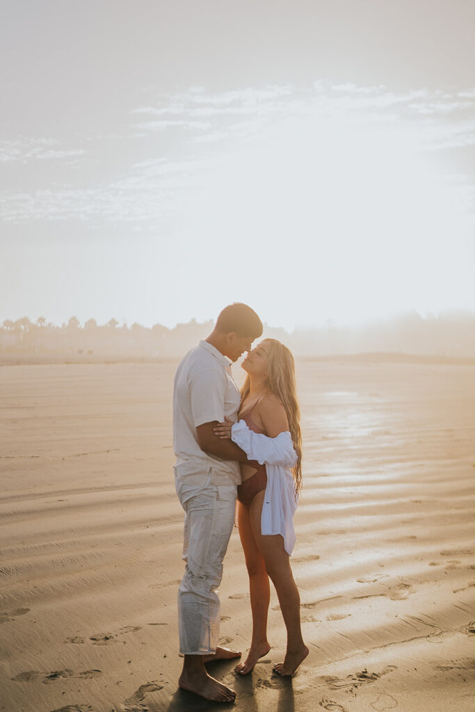 Couple embracing on the beach at sunrise in san diego california
